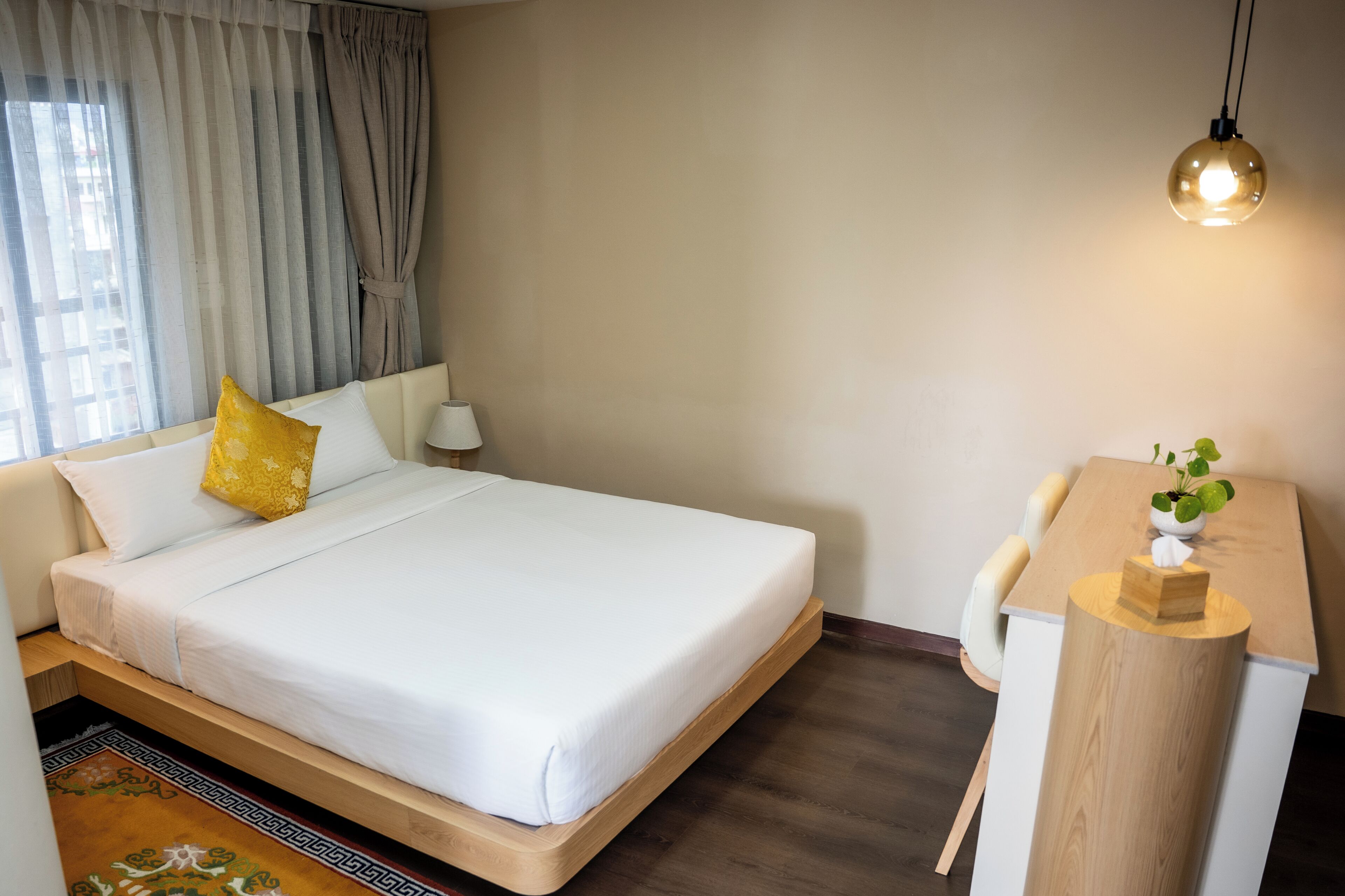 Una camera d'albergo con un letto, un comodino, una lampada e una piccola pianta.
