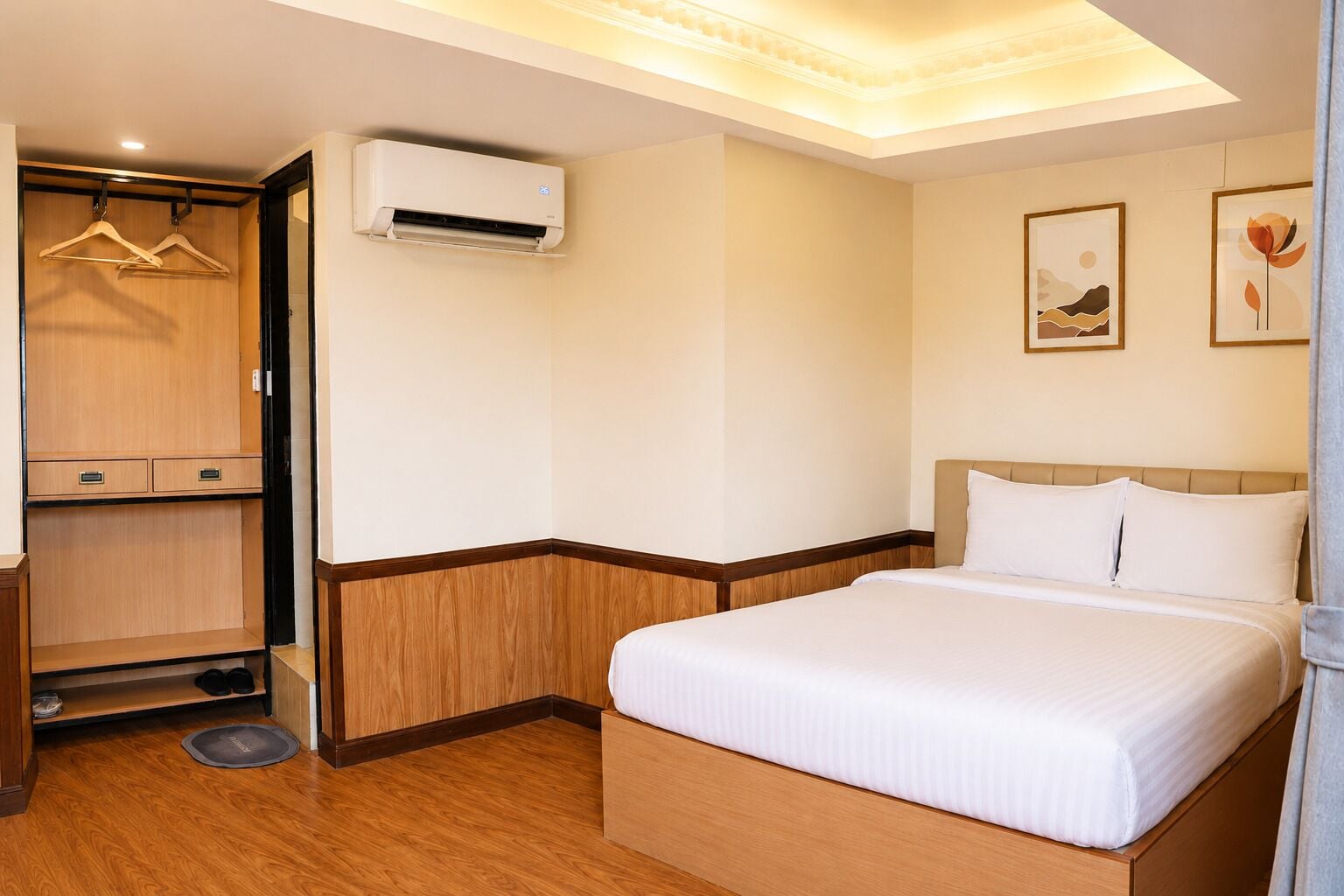A hotel room with a bed, a wardrobe, an air conditioning unit, and a pet bed.