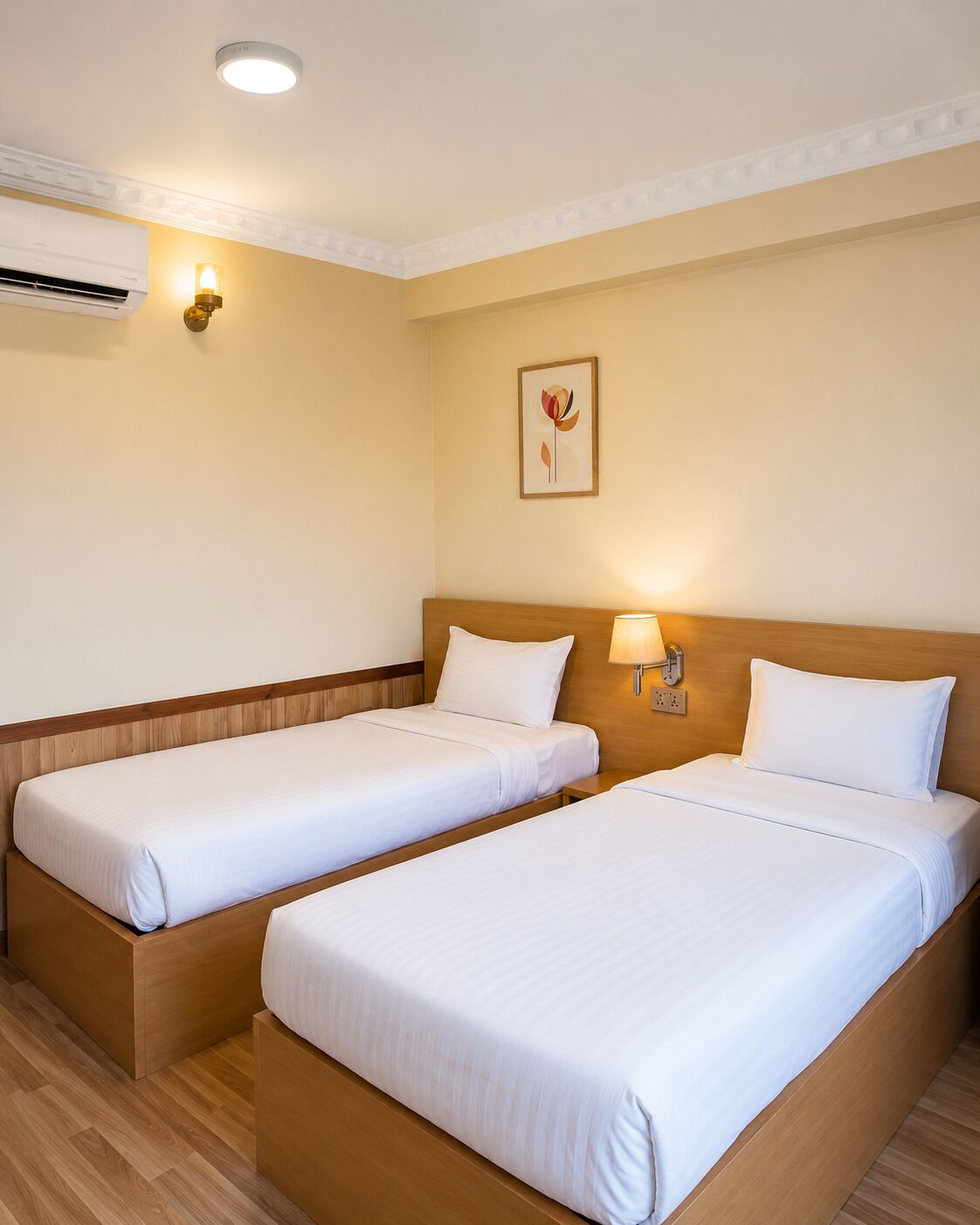 Een hotelkamer met twee eenpersoonsbedden, een plafondlamp, een airconditioner en een wandlamp.