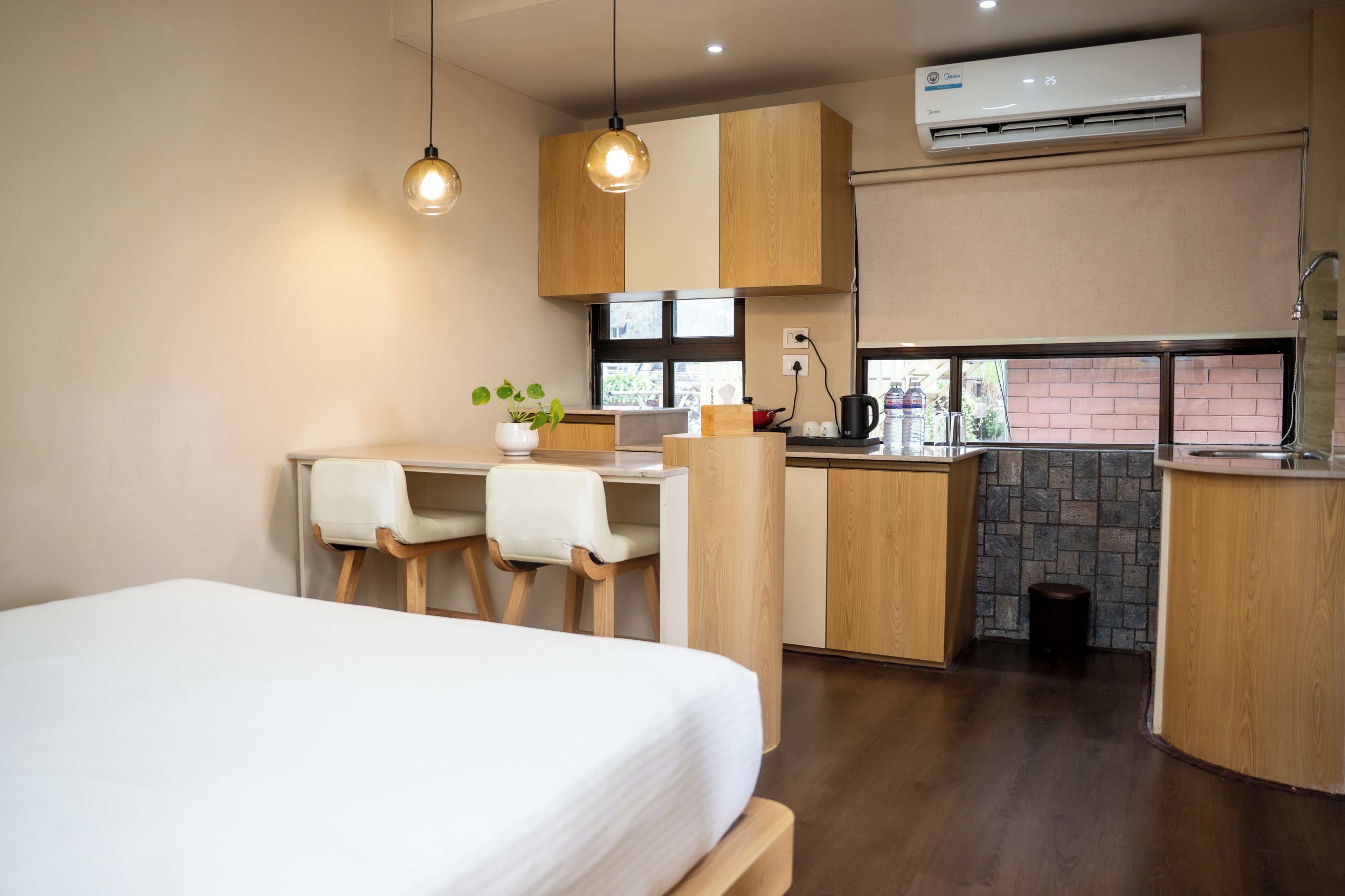 Een moderne keuken met houten kasten, een eethoek met een witte tafel en stoelen, en een bed met een witte matras.
