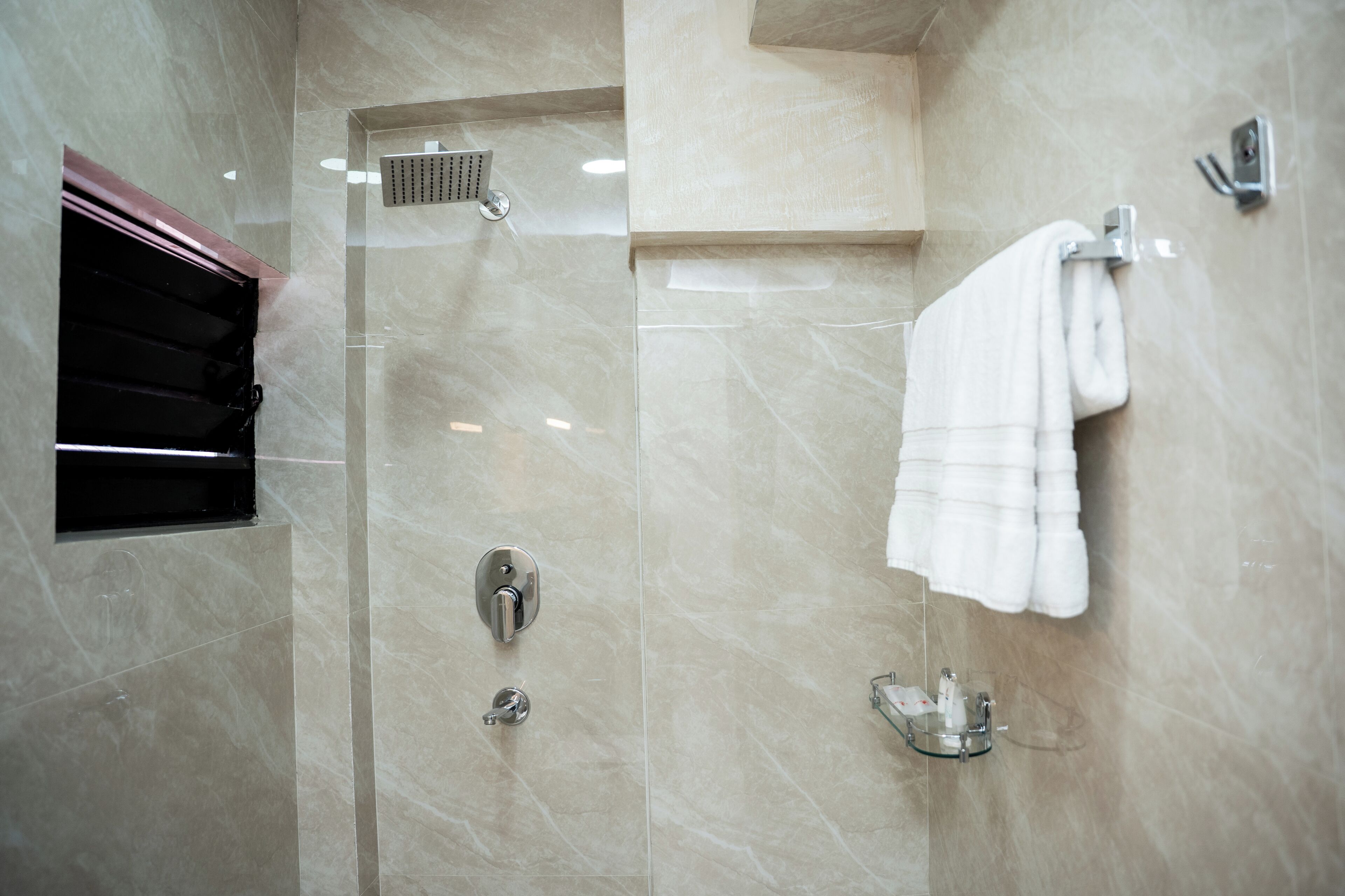 A modern bathroom with a glass-enclosed shower, a towel rack, and a toilet.