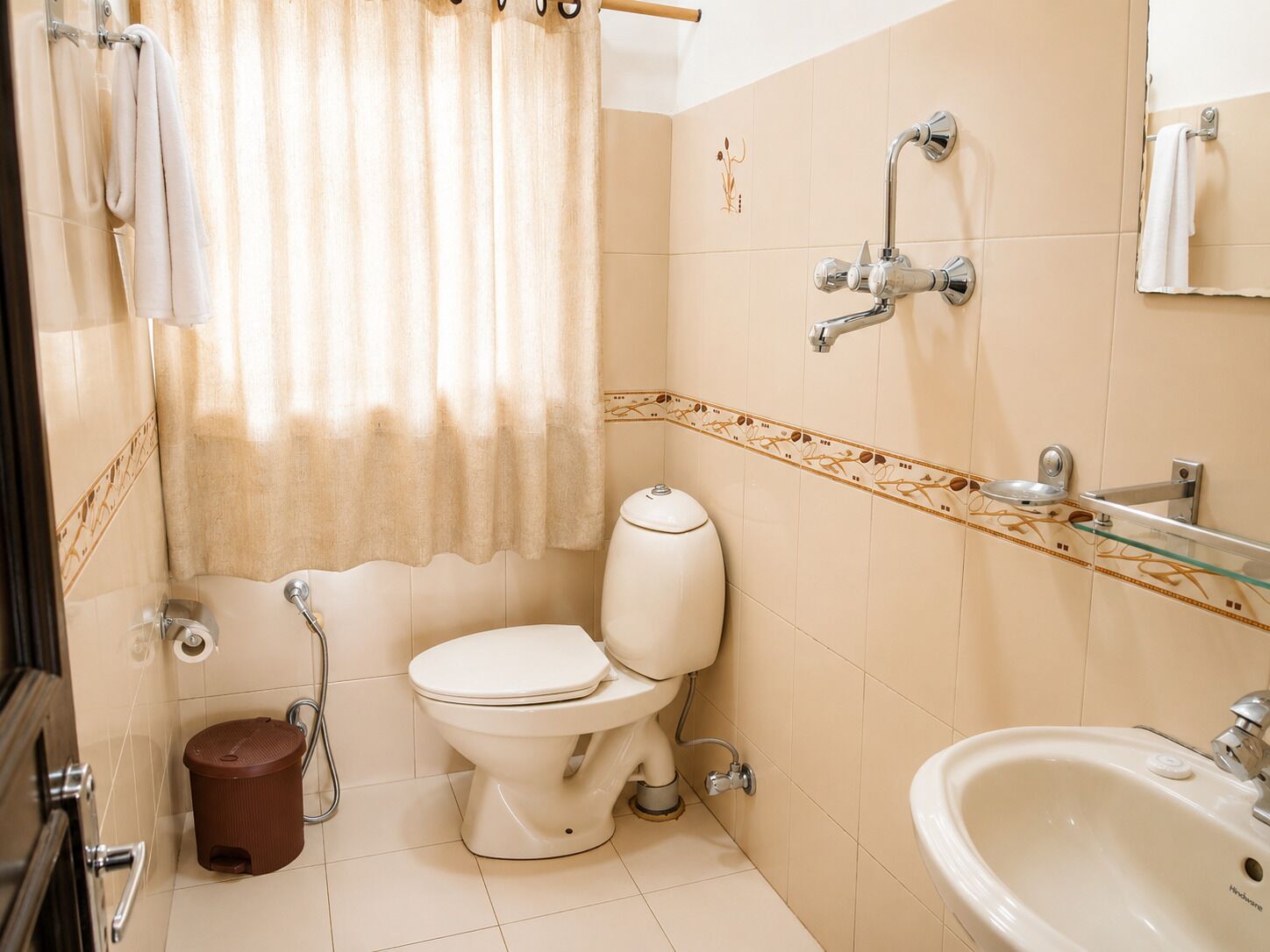 A bathroom with a toilet, bidet, sink, and shower curtain.