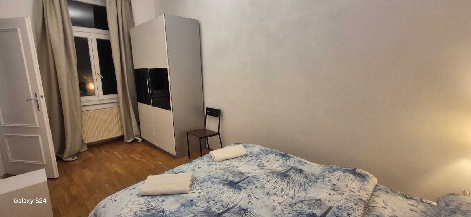 Une chambre à coucher avec un lit, une armoire, une chaise et une fenêtre.