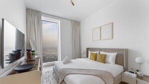 Ett modernt hotellrum med en stor säng, ett skrivbord, en stol och utsikt över staden.
