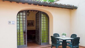 Een terras met een tafel en stoelen, een open doorgang naar een kamer en een bord op de muur.
