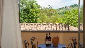 Un balcon avec une table, deux chaises et deux bouteilles de vin.