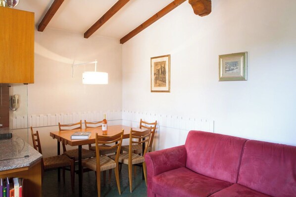 Un comedor con una mesa, sillas, un sofá rojo y dos cuadros en la pared.