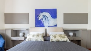 Une chambre d’hôtel avec deux lits, un grand tableau représentant un cheval et une vue sur la mer.