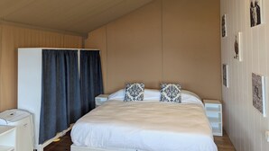 Un dormitorio con cama, armario, mesita de noche, ventilador y cuadros en la pared.