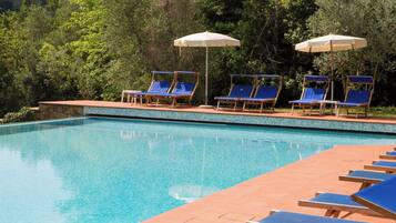 Una piscina con acqua cristallina, circondata da lettini e ombrelloni.