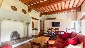 A spacious living room with a fireplace, wooden furniture, and a television mounted on the wall. - Country Resort in Impruneta with 2 bedrooms sleeps 6 (Impruneta)