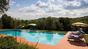 A swimming pool with lounge chairs and umbrellas, surrounded by trees and hills. - Country Resort in Impruneta with 2 bedrooms sleeps 6 (Impruneta)