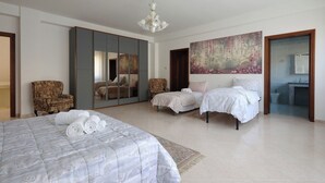 A bedroom with a large bed, two smaller beds, a chair, a wardrobe, and a painting. - Luxurious Mountain Villa With Pool in Fairytale-like Puglia (Roseto Valfortore)