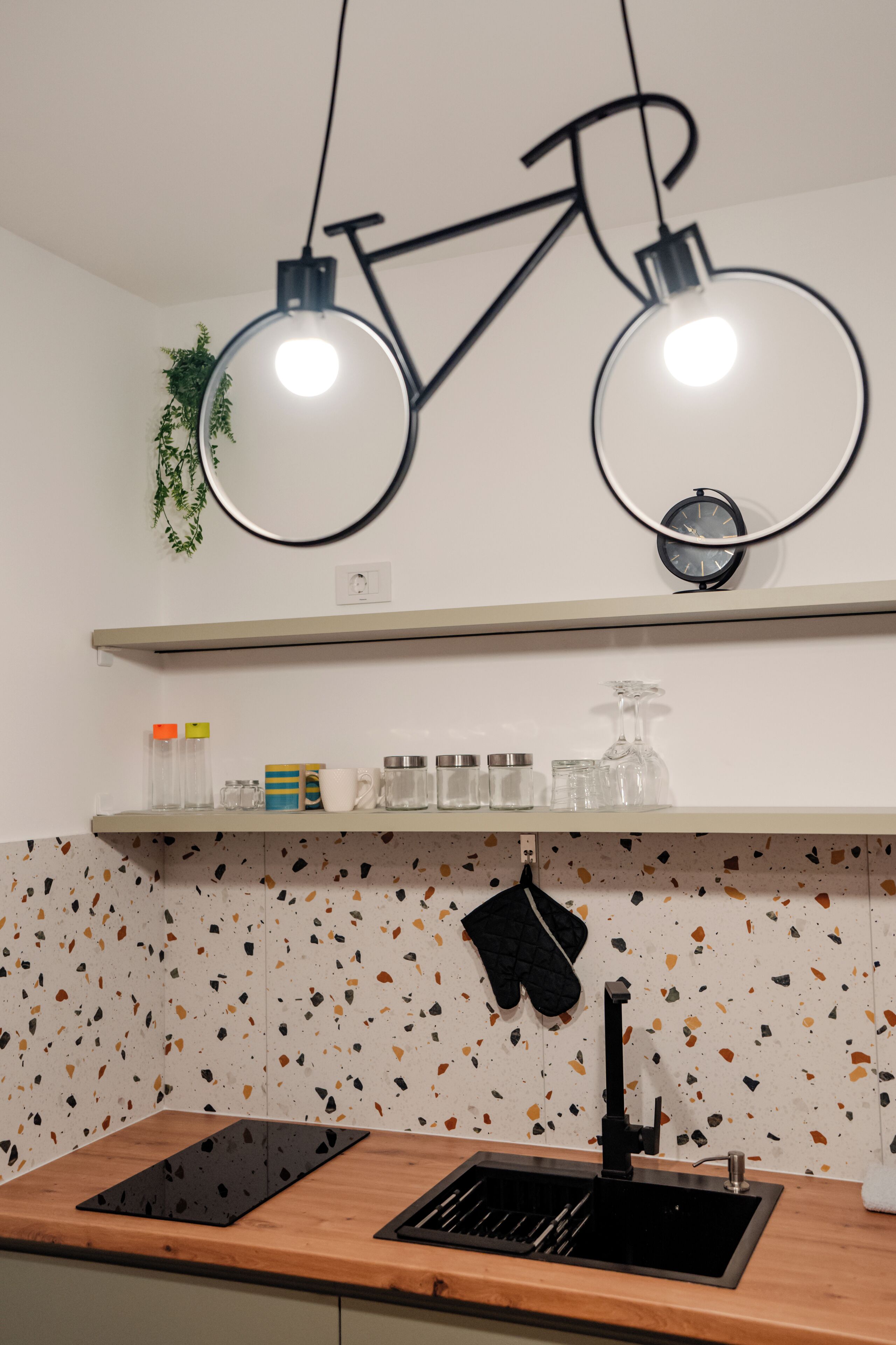 A kitchen with a countertop, sink, and a shelf above.