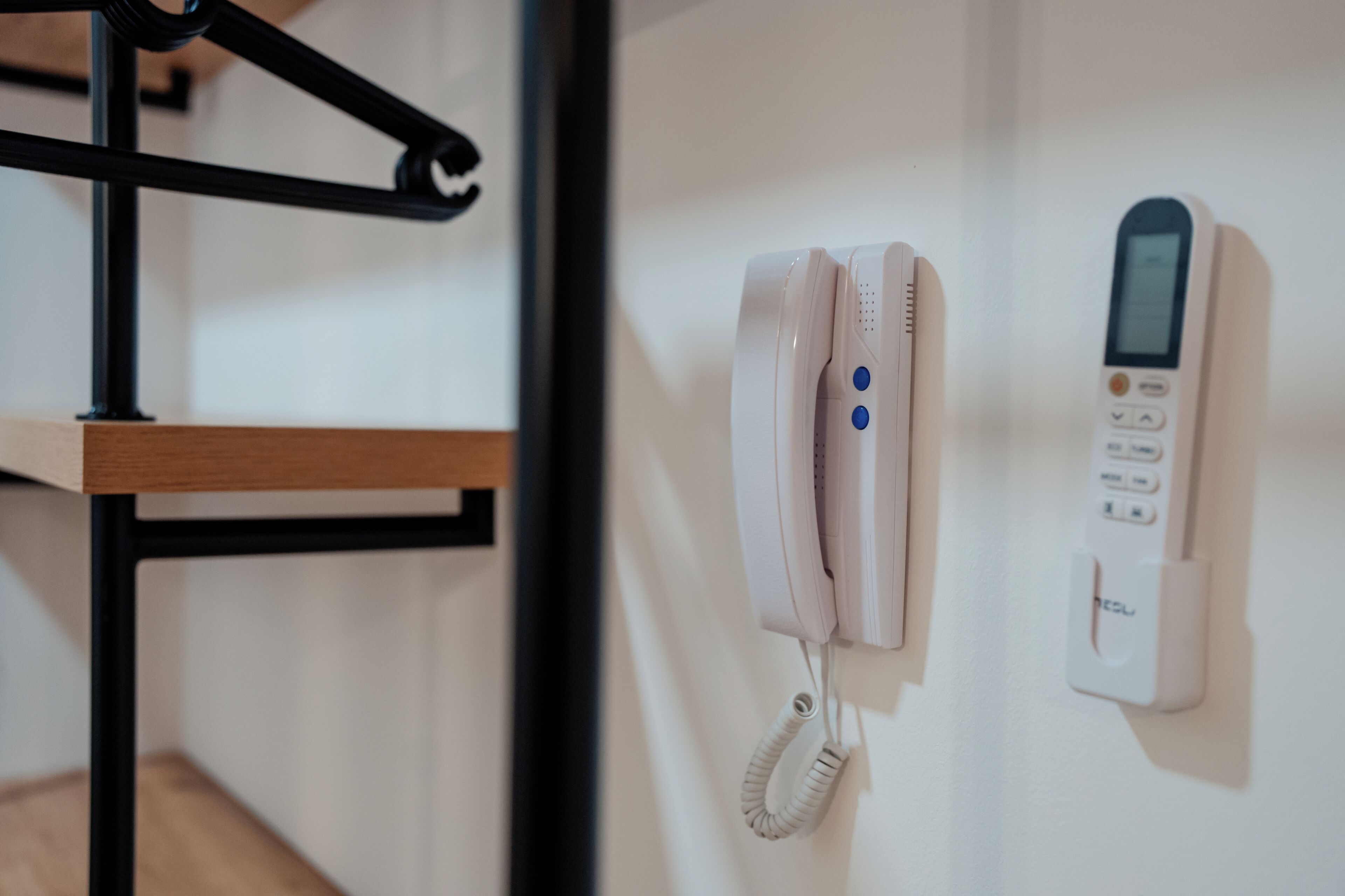 A white telephone and a digital device mounted on a wall.