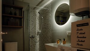 Casa de banho compacta com sanita, chuveiro e máquina de lavar roupa.