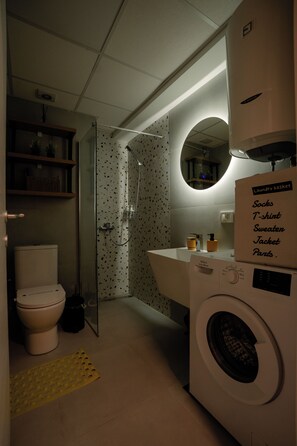 Ein kleines Badezimmer mit Toilette, Dusche und Waschmaschine.
