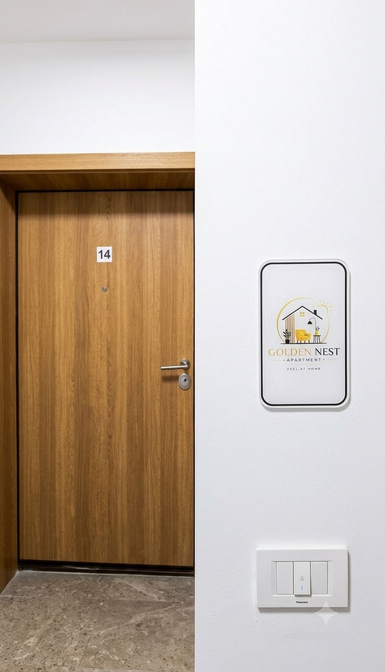 Una puerta de madera con una placa de número, un letrero en la pared que dice 'Golden Nest Apartment' y un interruptor de luz.