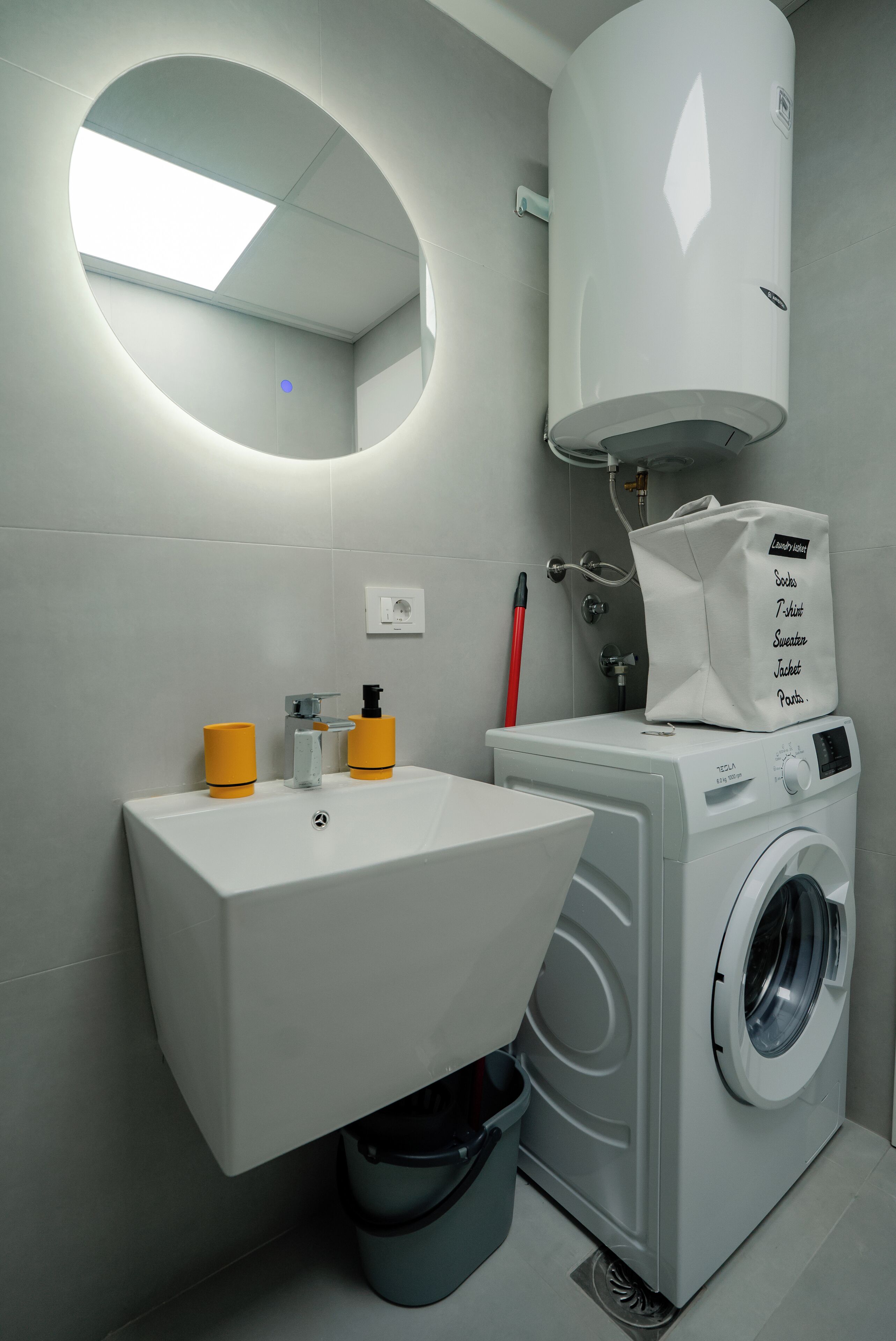 Une petite salle de bain équipée d’un lave-linge encastré, d’un lavabo et de toilettes.