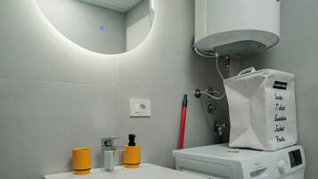 Une petite salle de bain équipée d’un lave-linge encastré, d’un lavabo et de toilettes.