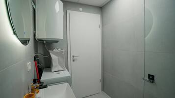 Un baño moderno con inodoro, lavamanos y zona de ducha.