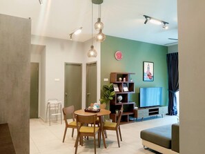 Un salon moderne comprenant un coin repas, un téléviseur à écran plat et une bibliothèque.