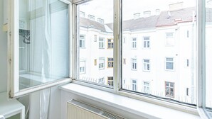 A room with a large window overlooking a row of white buildings with multiple windows. - Stylish 1BR Apartment In Vienna Center (Vienna)
