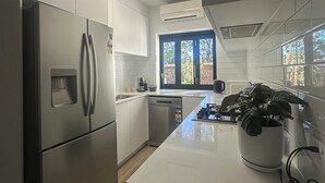 Een moderne keuken met roestvrijstalen apparatuur, een vaatwasser en een raam dat voor natuurlijk licht zorgt.