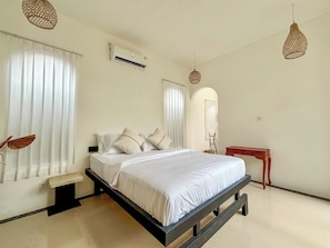 A bedroom with a bed, bedside tables, an air conditioning unit, and hanging light fixtures. - Ingrid Villa Ubud by AGATA (Ubud)