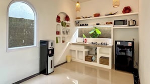 A compact kitchen with a built-in microwave, a coffee maker, and a refrigerator. There is a window providing a view of the outdoors. - Ingrid Villa Ubud by AGATA (Ubud)