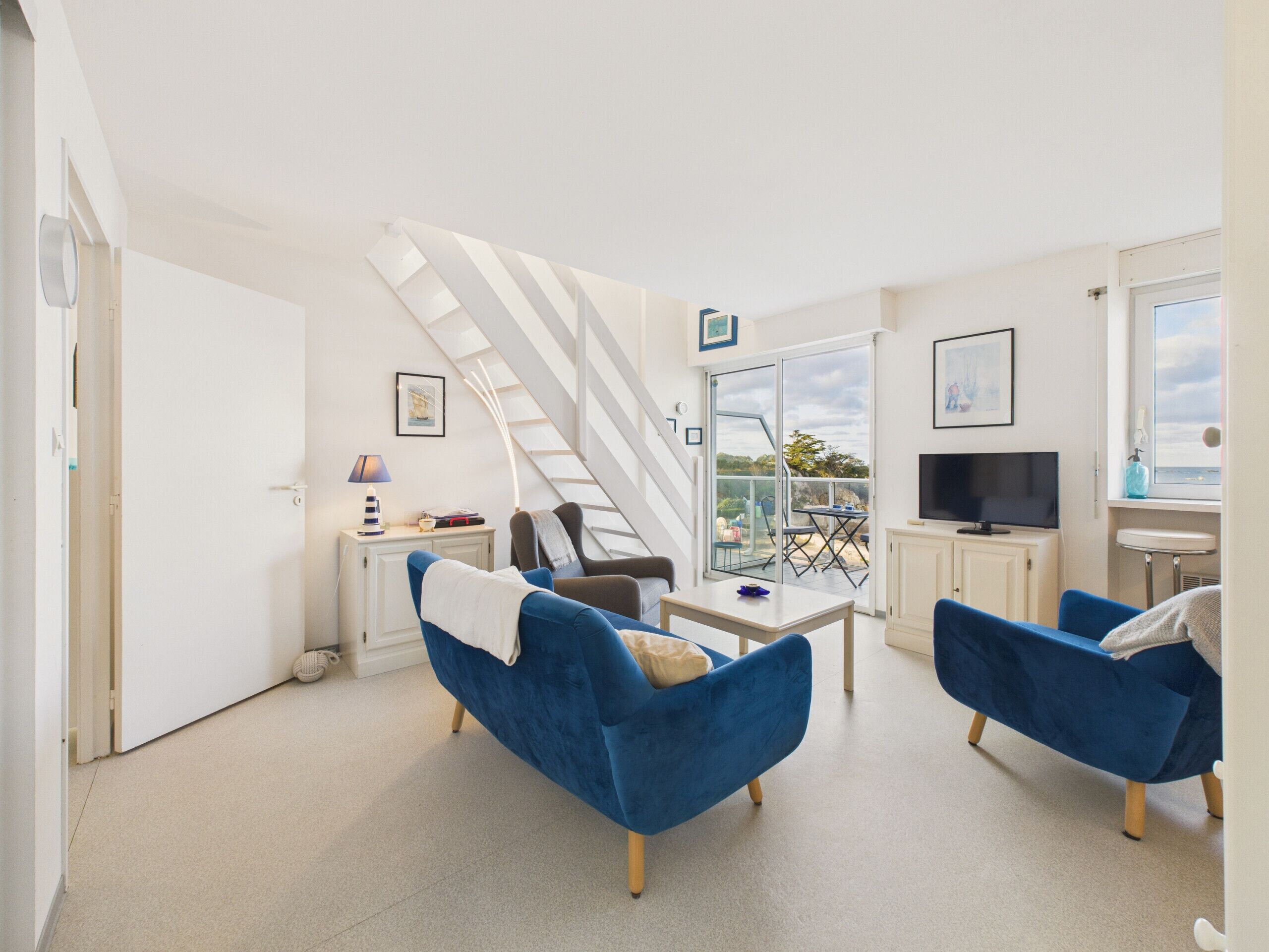 Un salon moderne avec un escalier, un téléviseur et un balcon offrant une vue dégagée.