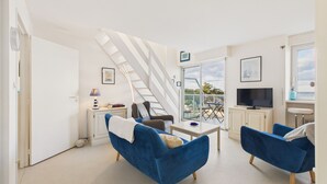 Een moderne woonkamer met een trap, een televisie en een balkon met uitzicht.
