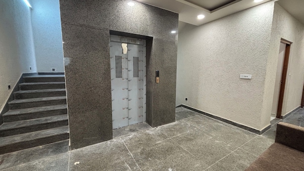 A modern hallway with a marble floor, a staircase, and a door with a security keypad. - Hotel Kajal Inn (Ajmer)