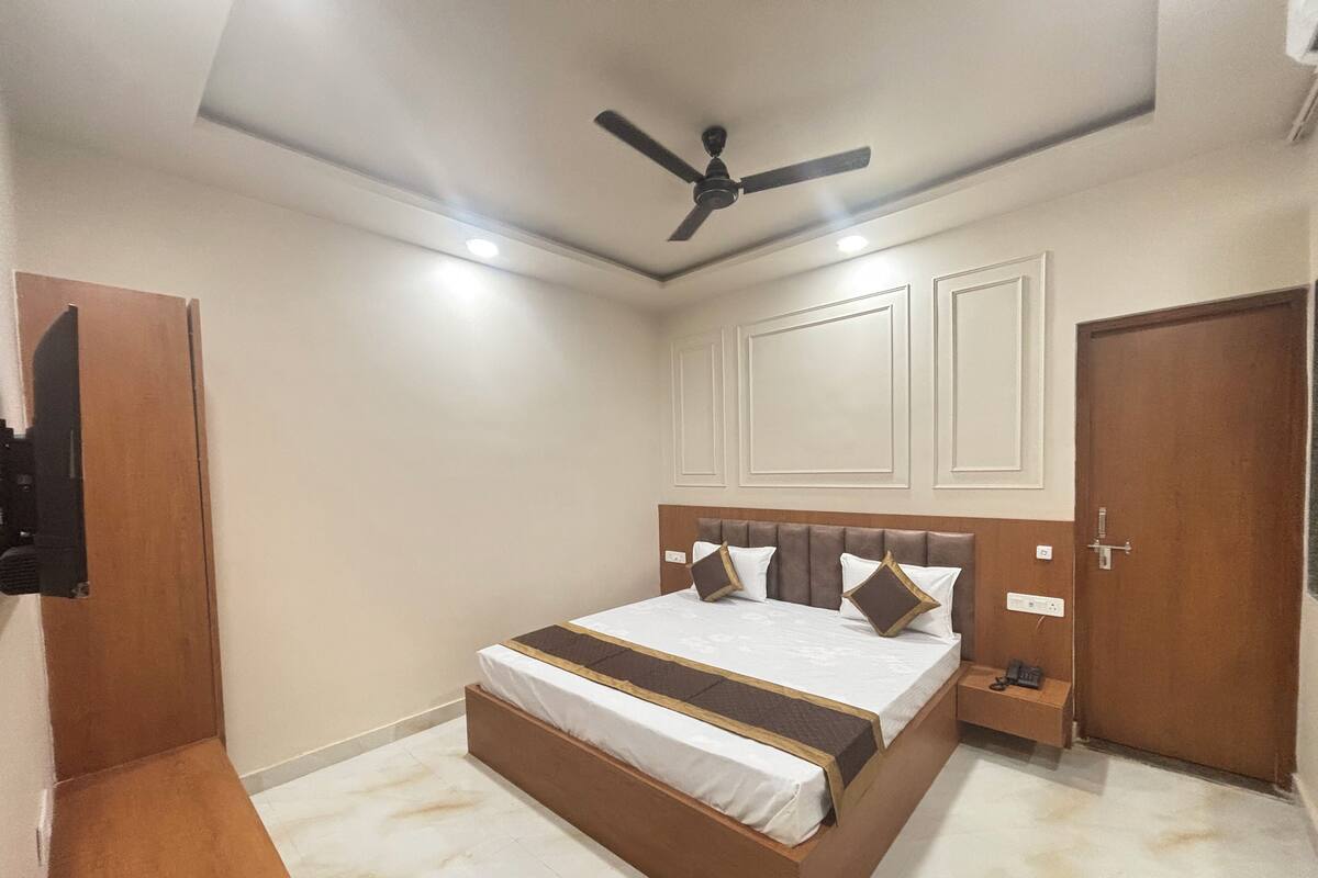 A bedroom with a bed, a ceiling fan, a nightstand, and a door.