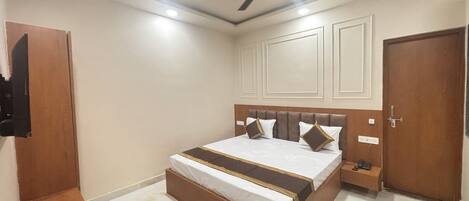 A bedroom with a bed, a ceiling fan, a nightstand, and a door.