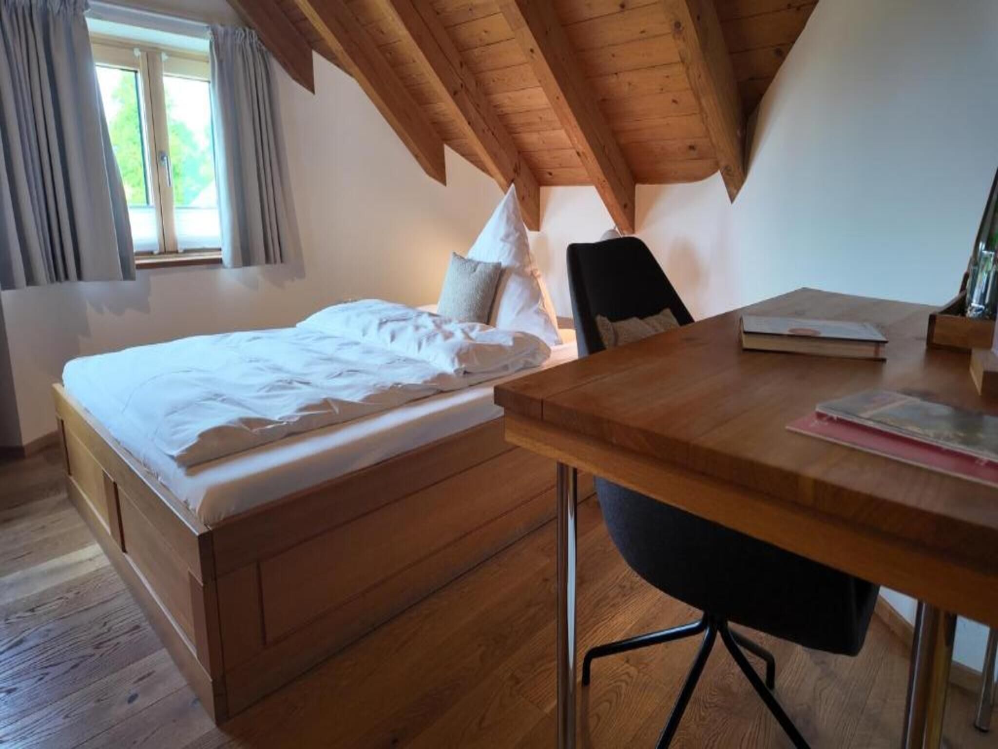 Un dormitorio con una cama de madera, un escritorio con silla y una ventana con cortinas.