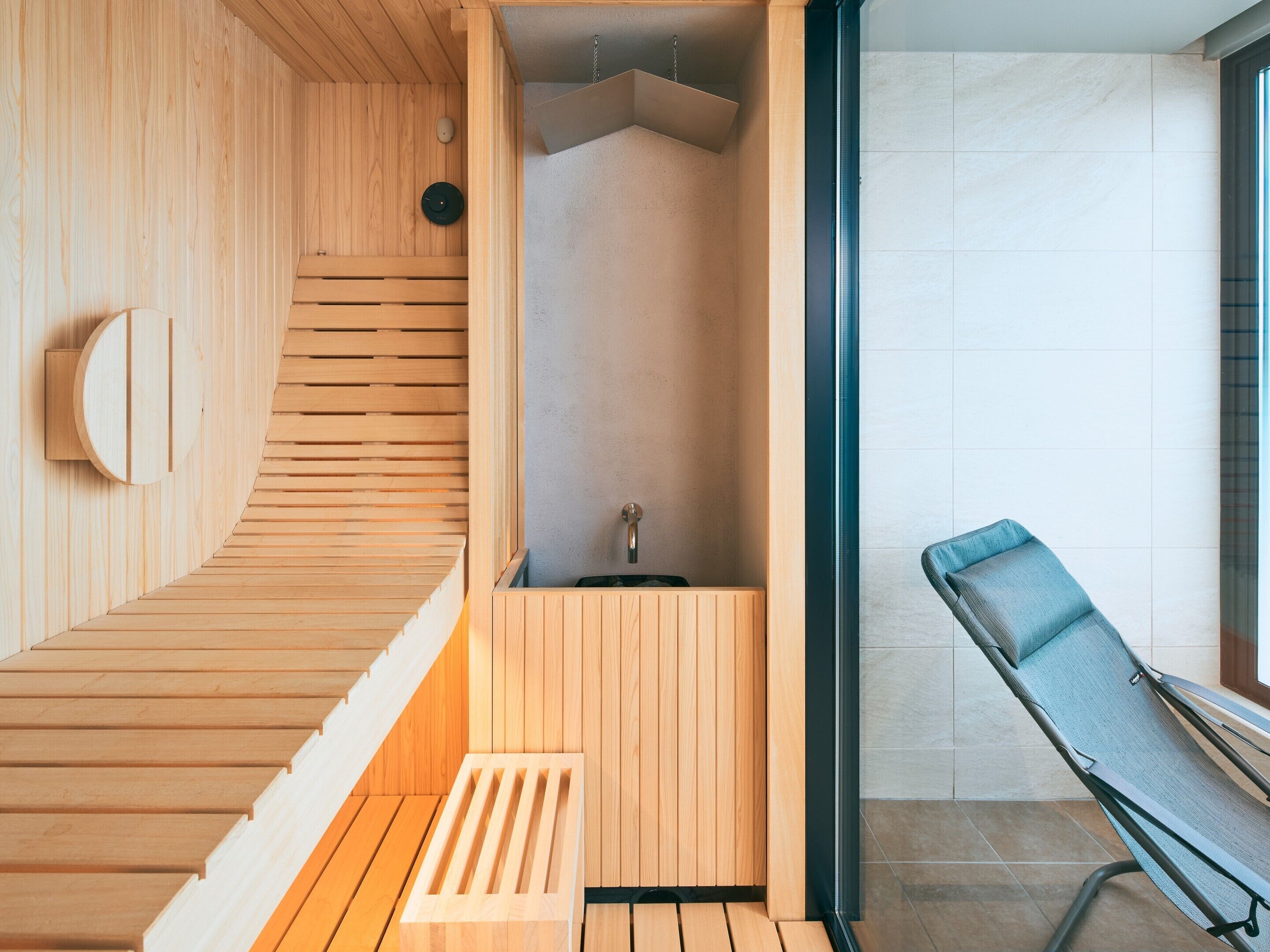 Un sauna en bois avec un banc, un petit lavabo et une fenêtre.