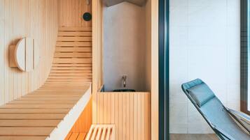 A wooden sauna with a bench, a small sink, and a window.