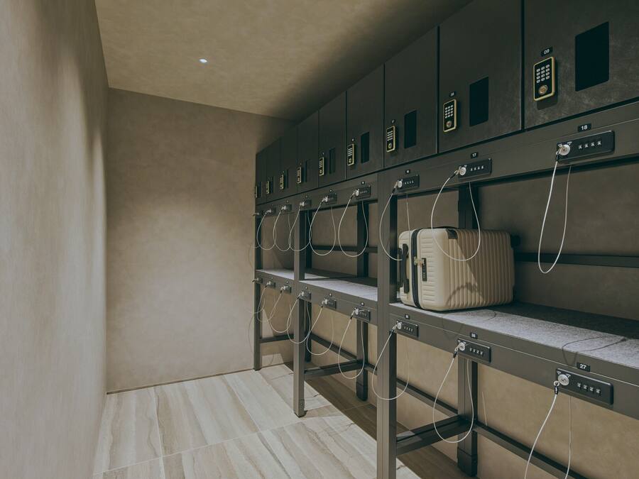 A row of lockers with numbered compartments, a suitcase on one of the lockers, and a tiled floor.