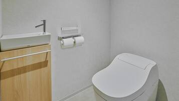 Uma casa de banho moderna com sanita, lavatório e dispensador de papel.