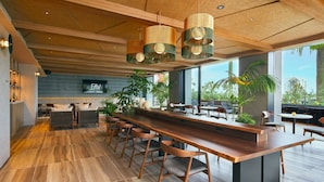 A modern bar area with a long counter, multiple stools, and a large window offering a view of the outdoors. - FAV LUX MIYAZAKI (Miyazaki)