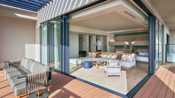 A modern interior with a large glass door leading to a living area, a sofa, a coffee table, and a bunk bed. - FAV LUX MIYAZAKI (Miyazaki)