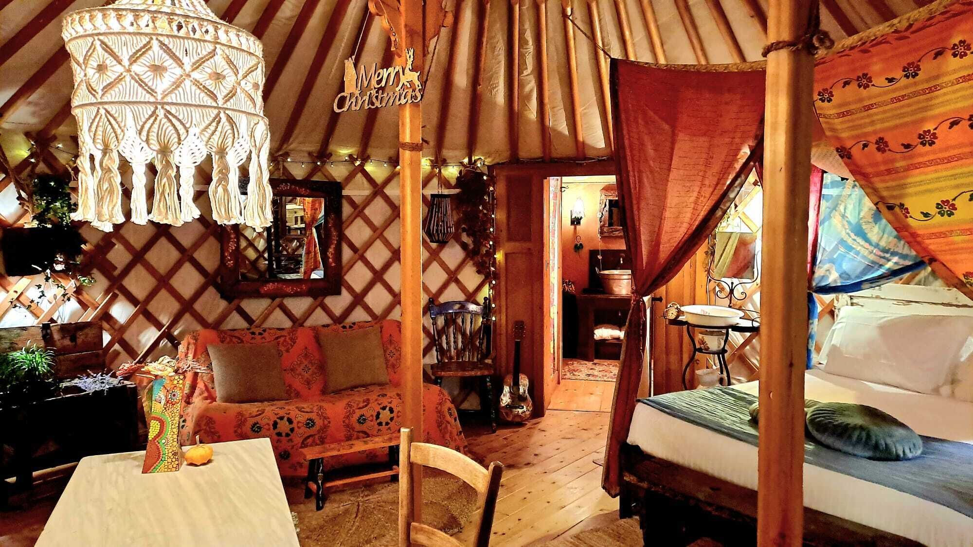 A cozy, rustic interior with a wooden bench, a hanging light fixture, and a bed with a canopy.