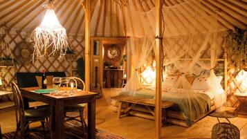 Una tenda accogliente e luminosa con un letto, un'area pranzo e una piccola cucina.