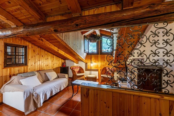 A cozy wooden cabin interior with a sofa, chairs, a fireplace, and a hanging plant. - 🏠 PROPERTY DESCRIPTIONWelcome to Casa Alpina, in the heart of La Thuile, Valle d’Aosta. A typical mountain apartment, cozy and comfortable, immersed in the tranquility of an alpine village. Ideal for those seeking relaxation, nature, and ski slopes  (La Thuile)