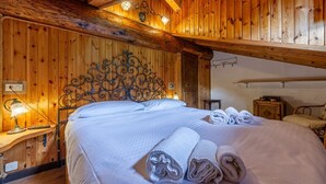A wooden room with a bed, a nightstand, and a lamp. - 🏠 PROPERTY DESCRIPTIONWelcome to Casa Alpina, in the heart of La Thuile, Valle d’Aosta. A typical mountain apartment, cozy and comfortable, immersed in the tranquility of an alpine village. Ideal for those seeking relaxation, nature, and ski slopes  (La Thuile)