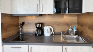 Eine moderne Küche mit Spüle aus Edelstahl, einer Kaffeemaschine, einem Wasserkocher und einer Mikrowelle.