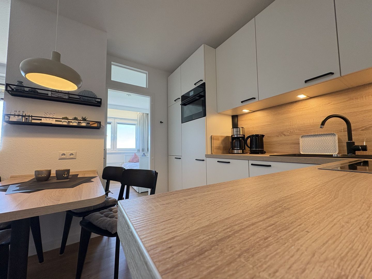 A modern kitchen with a wooden countertop, a built-in stove, and a coffee maker.