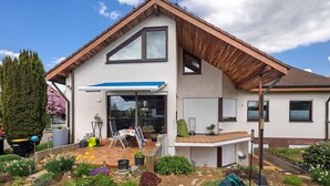 A modern house with a sloped roof, a covered patio, and a garden with various plants. - Apartment Teckblick with Wi-Fi (Kirchheim unter Teck)