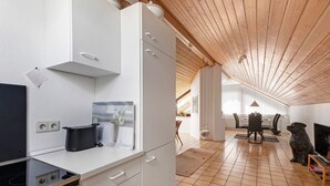 A modern kitchen with white cabinetry, a stove, and a dining area with a table and chairs. - Apartment Teckblick with Wi-Fi (Kirchheim unter Teck)